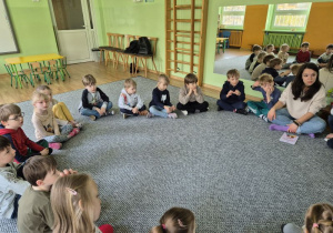Prowadząca prezentuje dzieciom książkę na temat smutku