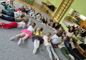 Dzieci słuchają opowiadania czytanego przez prowadzącą zajęcia