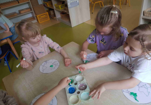 Dzieci stemplują model Ziemi patyczkami kosmetycznymi umoczonymi w farbie.