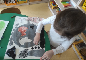 Dziewczynka rysuje zanieczyszczoną planetę.