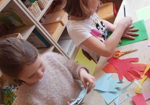 Dziewczynki odrysowują dłonie i wycinają je z kolorowego papieru