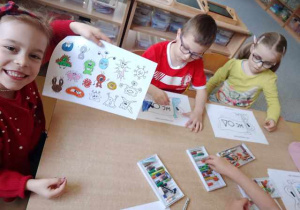 Tosia prezentuje swoją pracę dotyczącą mycia rąk, w tle widać dzieci kolorujące swoje ilustracje