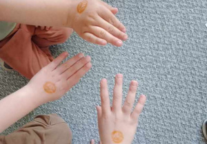 Zdjęcie przedstawia dłonie dzieci ze stempelkiem związanym z programem edukacyjnym