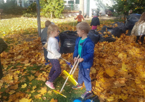 Dzieci grabią jesienne liście