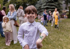 Chłopiec stoi i prezentuje tatuaż na swojej ręce