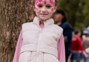 Dziewczynka z namalowanym motylem na twarzy pozuje do zdjęcia