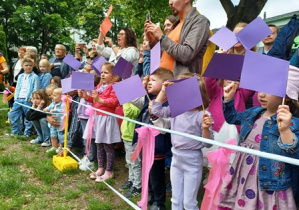 Dzieci śpiewają piosenkę machając fioletowymi flagami
