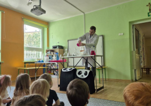 Mężczyzna ubrany w biały fartuch przelewa różowy płyn do szklanych naczyń