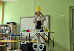 Kobieta ubrana na biało wypełnia balon dwutlenkiem węgla umieszczonym w kolbie