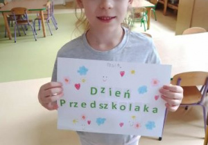 Dziewczynka prezentuje napis Dień Przedszkolaka