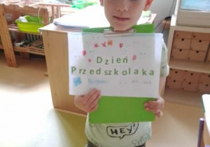 Chłopiec prezentuje napis Dzień Przedszkolaka