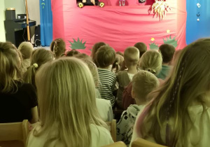 Dzieci oglądają przedstawienie siedząc na widowni, na scenie koń, myszka i żuczek