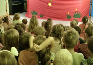 Dzieci oglądają przedstawienie siedząc na widowni, na scenie biedronka i żuczek
