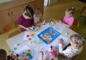 Dzieci wyklejają kropkę z kolorowych kół