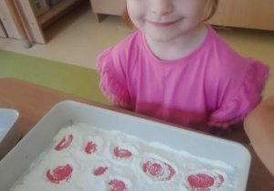 Dziewczynka jest zadowolona ze swojej pracy wykonanej w mące