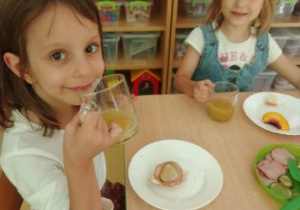 Dziewczynki piją świeżo wyciśnięty sok z jabłek