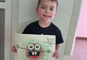 Chłopiec prezentuje wykonaną przez siebie pracę plastyczną pt. "Potworek pełen emocji"