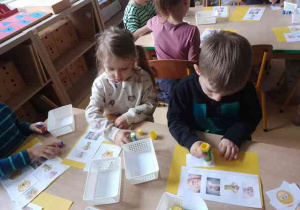 Wiktora i Tytus doklejają do kartki papieru ilustracje określonych emocji