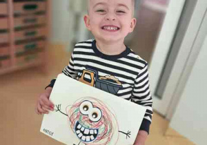 Antoś prezentuje wykonaną przez siebie pracę plastyczną pt. "Potworek pełen emocji"