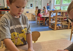 Chłopiec nakleja naklejkę określającą jego nastrój na swoją wizytówkę