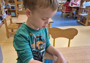 Chłopiec nakleja naklejkę określającą jego nastrój na swoją wizytówkę