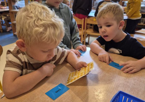 Chłopiec wybiera naklejkę z nastrojem, dwóch chłopców siedzi obok i czekają na swoją kolei