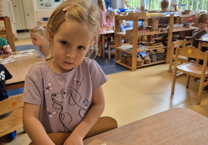 Dziewczynka nakleja naklejkę określającą jej nastrój na swoją wizytówkę