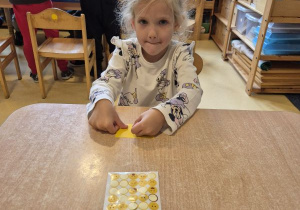 Dziewczynka nakleja naklejkę określającą jej nastrój na swoją wizytówkę