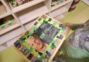 Dziewczynka odkłada swoją pracę przedstawiającą portret Marii Montessori na wystawę przed salą