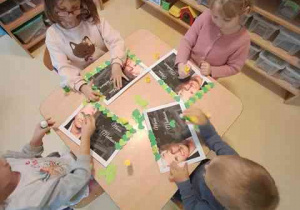 Dzieci w czasie działań plastycznych doklejają elementy kolorowego papieru i tworzą ramkę do portretu Marii Montessori