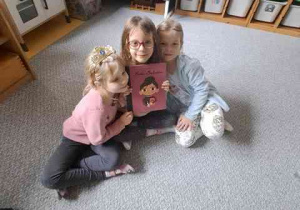 Dziewczynki pozują do pamiątkowego zdjęcia z książeczką o Marii Montessori