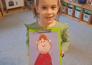 Tosia trzyma w dłoniach namalowany przez siebie rysunek przedstawiający Marię Montessori