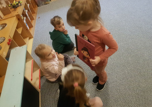 Dziewczynka przekazuje koleżance książkę o Marii Montessori.