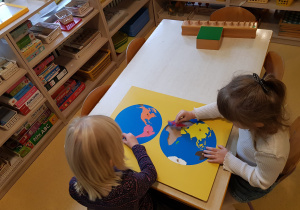 Dziewczynki układają puzzle kontynenty.