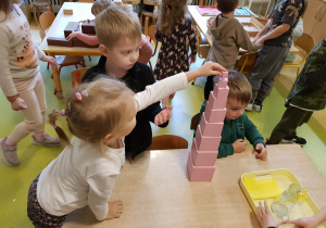 Dzieci układają różowa wieżę.