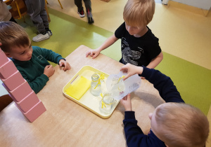 Chłopcy przelewają wodę.