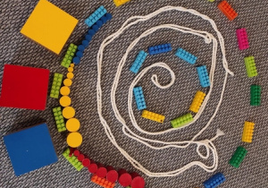 Praca konstrukcyjna z wykorzystaniem klocków i kolorowych cylindrów przedstawiająca ,,Ślimaka''.