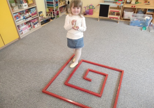 Dziewczynka podczas ćwiczenia ciszy ,,chodzenie w labiryncie z dzwoneczkiem".