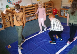 Dzieci idą po elipsie z dzwonkiem w ręku podczas ćwiczenia ciszy