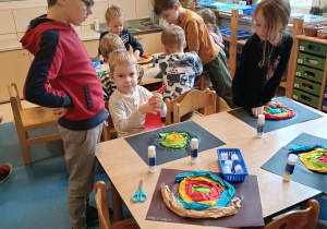 Dzieci siedzą przy stoliku i wykonują pracę plastyczną - ślimaka