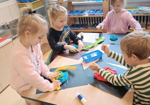 Dzieci siedzą przy stoliku i wykonują pracę plastyczną - ślimaka