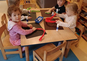 Dzieci siedzą przy stoliku i wykonują pracę plastyczną - ślimaka