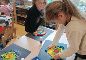 Dzieci siedzą przy stoliku i wykonują pracę plastyczną - ślimaka