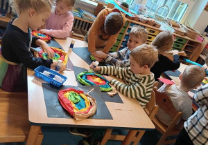 Dzieci siedzą przy stoliku i wykonują pracę plastyczną - ślimaka