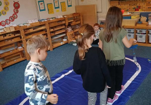 Dzieci idą po elipsie z dzwonkiem w ręku podczas ćwiczenia ciszy