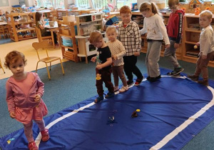 Dzieci idą po elipsie z dzwonkiem w ręku podczas ćwiczenia ciszy