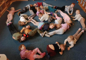 Dzieci utworzyły ślimaka z własnych ciał leżąc na dywanie