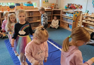 Dzieci idą po elipsie z dzwonkiem w ręku podczas ćwiczenia ciszy