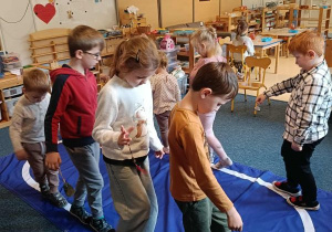 Dzieci idą po elipsie z dzwonkiem w ręku podczas ćwiczenia ciszy