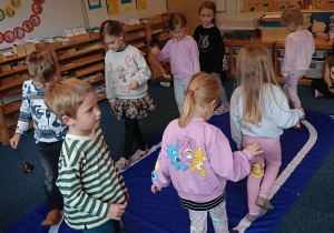 Dzieci idą po elipsie z dzwonkiem w ręku podczas ćwiczenia ciszy